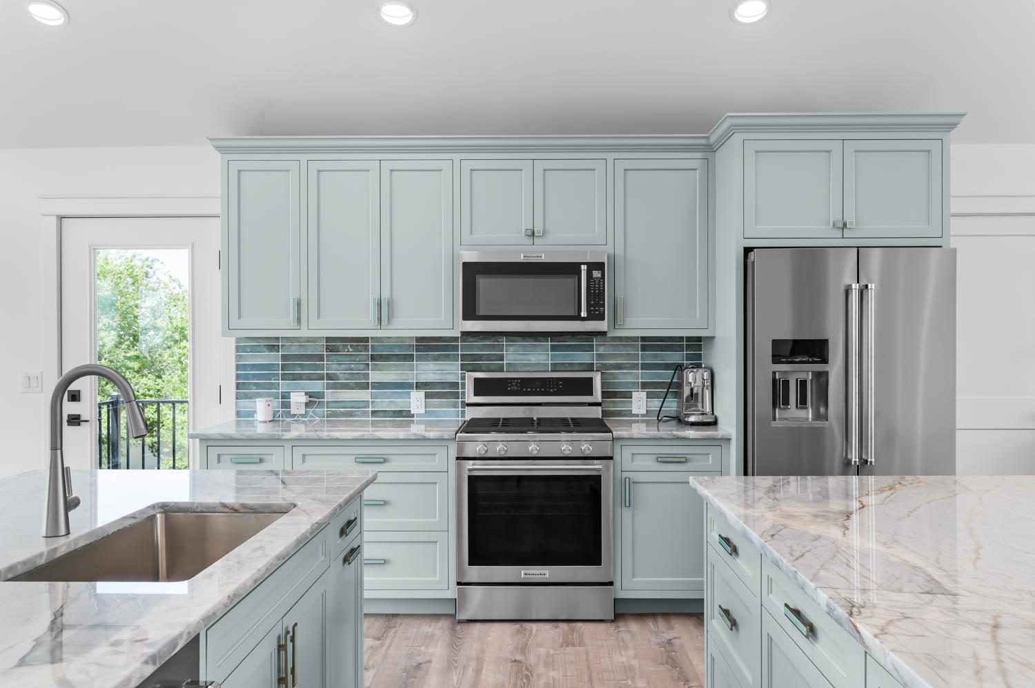 Kitchen remodel with sage-blue shaker cabinets, marble waterfall island, and mosaic tile backsplash