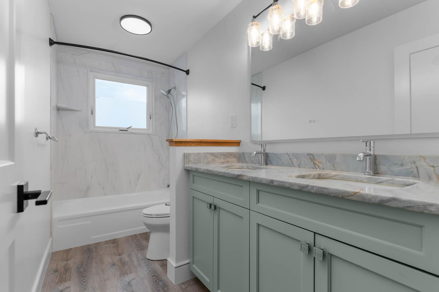Bathroom remodel with sage-green double vanity, marble tub surround, and a curved shower rod