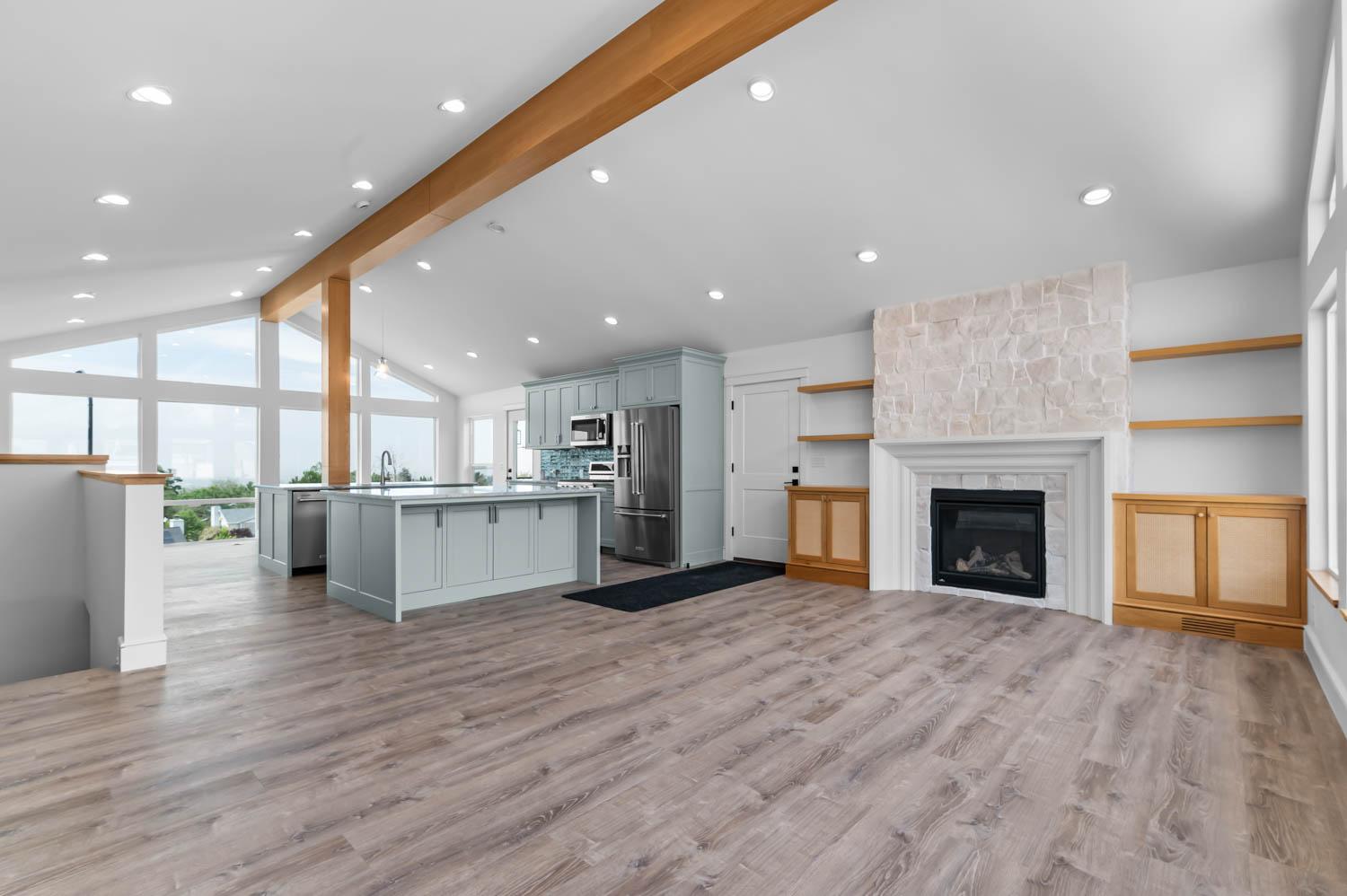 Whole-home remodel with a stone fireplace and the kitchen visible in the background
