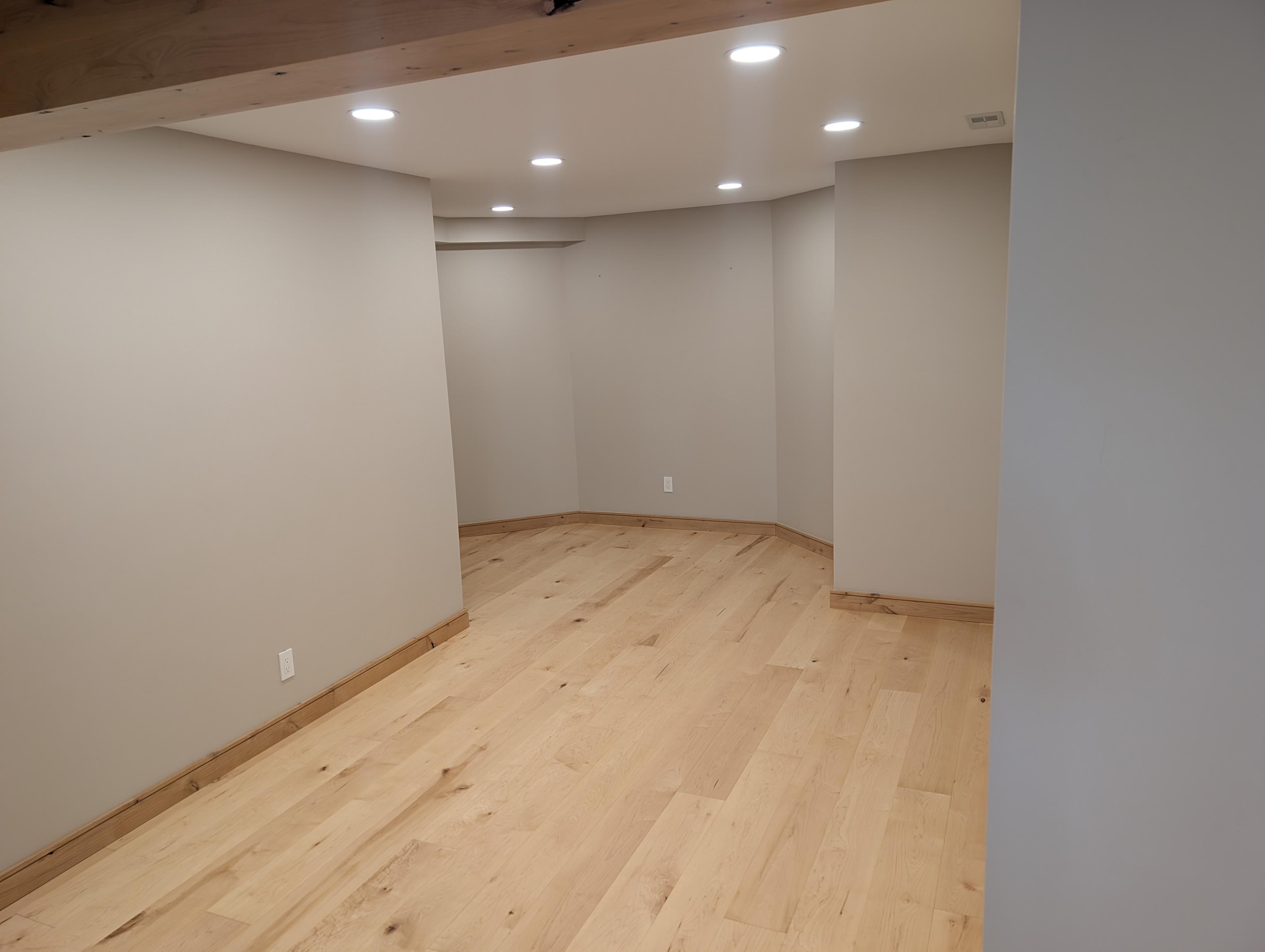 Finished basement with wide-plank hardwood flooring and recessed lighting